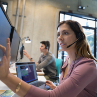Man and woman interacting with their desktop monitors while on headset calls.